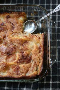 a casserole in a glass dish with a spoon on the side and a checkered table cloth