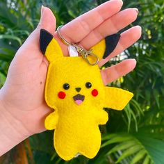 a hand holding a keychain shaped like a pikachu