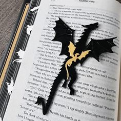 an open book with a black and gold dragon cut out of it's pages