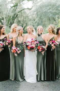 a group of women standing next to each other wearing dresses and holding bouquets in their hands