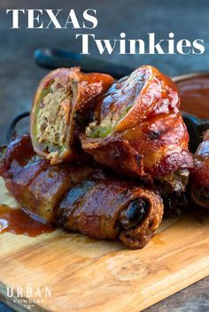 some bacon wrapped up and sitting on top of a cutting board with sauce in the background