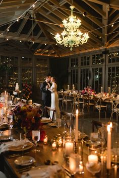 a bride and groom standing next to each other in front of a table with candles