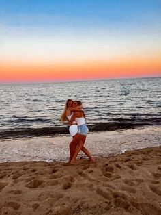 two women hug on the beach at sunset