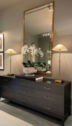 a large mirror sitting on top of a dresser next to a vase filled with flowers