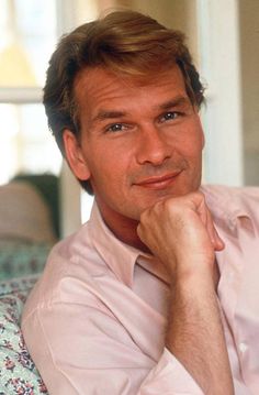 a man sitting on top of a couch with his chin resting on his hand and looking at the camera