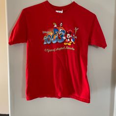 a red tshirt with mickey mouse and friends on it hanging from a door