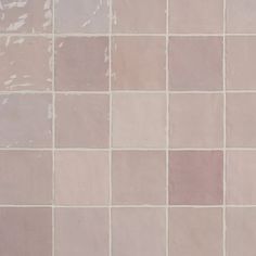 a white toilet sitting in front of a tiled wall with pink and grey tiles on it