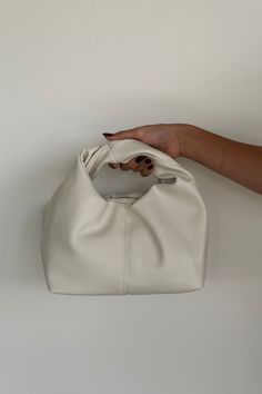 Introducing the Misty Handle Bag: a soft, semi-structured rectangular bag with a wide base, featuring two inner compartments, including a zip pouch. The top opening has a magnetic clasp closure, and the bag is highlighted by a statement wrap handle. Finished with a cotton inner lining, it combines practicality and style! Available in Bone; style with a new Fall outfit! Details: Two Inner Compartments Including with Zip Pouch Top Opening with Magnetic Clasp Closure Statement Wrap Handle Cotton In