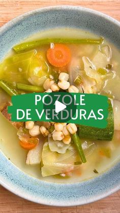 a bowl filled with soup and vegetables sitting on top of a wooden table next to a green sign