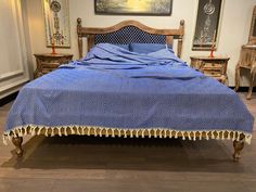 a bed covered in a blue blanket sitting on top of a hard wood floor next to two nightstands