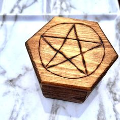 a wooden box with a pentagram on it sitting on a marble counter top,