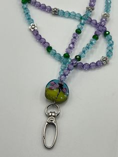 a beaded necklace with charms and beads hanging from it's sides on a white surface