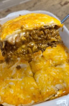 a close up of a plate of food with cheese and meat on it, being held by a fork