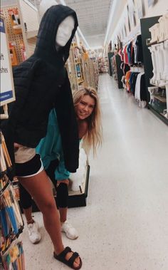 a woman standing next to a stuffed animal in a store