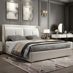 a modern bedroom with gray walls and white bedding, gold trimming on the headboard