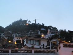 a hill with many houses on it and a cross at the top in the distance