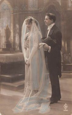 an old photo of a man and woman in wedding attire standing next to each other