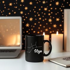 a black coffee mug sitting on top of a white desk next to a laptop computer