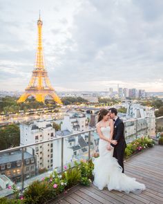 a bride and groom pose for a photo in front of the eiffel tower