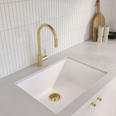 a white kitchen sink sitting under a faucet next to a wooden cutting board