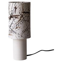 a white lamp with black and brown designs on it's base is plugged into a cord