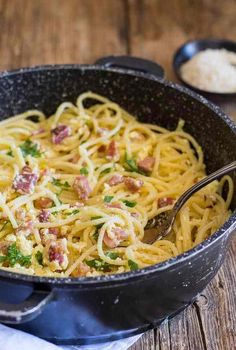 pasta with bacon and parmesan cheese in a skillet on a wooden table