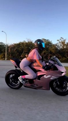 a woman riding on the back of a pink motorcycle