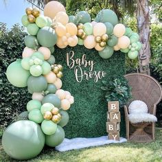 a baby shower backdrop with balloons and greenery in the shape of an arch is shown