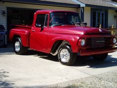 an old red truck parked in front of a house