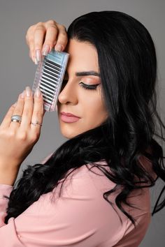 a woman with long black hair is holding a comb in her hand and looking at the camera