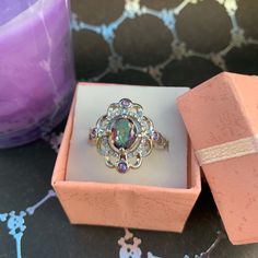 a ring in a pink box next to a candle