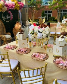 a table set up for a party with pink and white flowers in vases on top