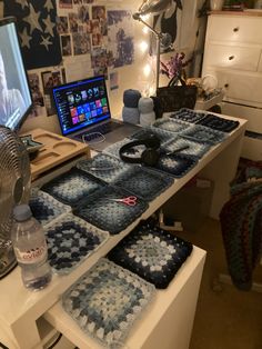 a laptop computer sitting on top of a white desk covered in blue crochet