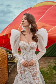 a woman in a wedding dress standing next to a hot air balloon with her hands on her hips