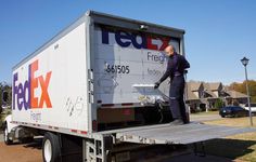 a man standing on the back of a fedex truck