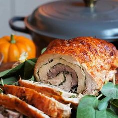 a meatloaf roll cut in half on a plate with greens and pumpkins