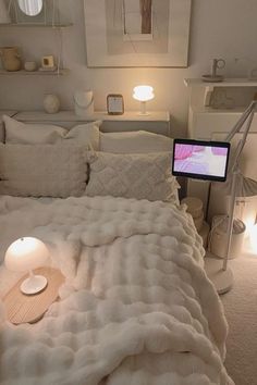 a bed with white blankets and pillows in a bedroom next to a lamp on the nightstand