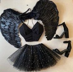 an angel costume with black wings and heels on the floor next to high heeled shoes