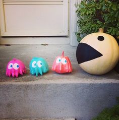 three plastic monsters sitting on the steps next to a pumpkin and an orange ball in front of a door