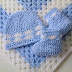 blue and white crocheted baby booties laying on top of a knitted blanket