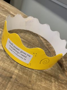 a yellow plastic crown sitting on top of a wooden table next to a sign that says god's power gives me good things