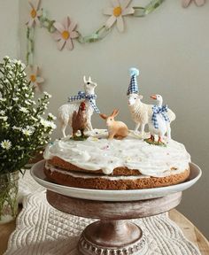 a cake with frosting and figurines of animals on it sitting on a table