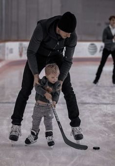 a man teaching a little boy how to play ice hockey