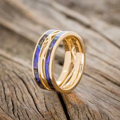 two gold wedding bands with blue opal inlays on top of each other