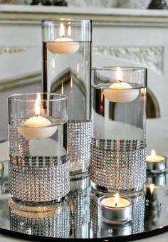 candles are lit in glass vases on a table