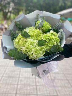 a bouquet of green and white flowers in someone's hand