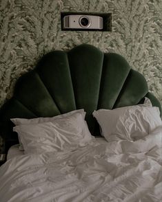 a camera mounted on the side of a wall above a bed with white sheets and pillows