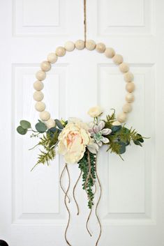 a wreath with flowers and greenery hangs on the front door, decorated with wood beads