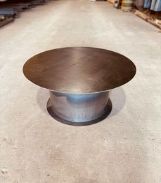 a round metal table sitting on top of a cement floor