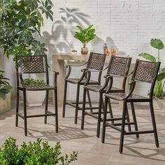 a set of four chairs sitting on top of a patio next to a potted plant